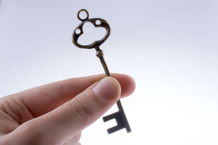 hand holding a  retro styled metal key  on a white backgroundの写真素材