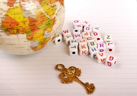 Globe, key and cube letters of alphabet side by side on a white paperの写真素材