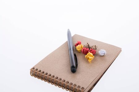 Crumpled paper and pollpoint pen on a spiral notebook on white backgroundの写真素材