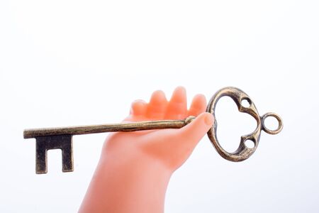 Doll holding a key on a white backgroundの写真素材