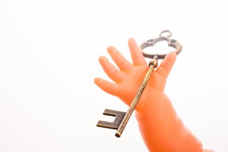 Doll holding a key on a white backgroundの写真素材