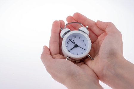 Alarm clock in hand on white backgroundの写真素材
