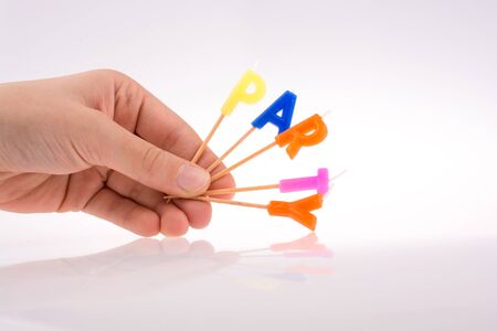 Color candles in hand on sticks write the word partyの写真素材