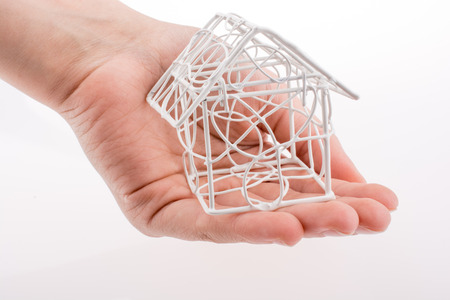 Little  model house made of white metal wire in handの写真素材
