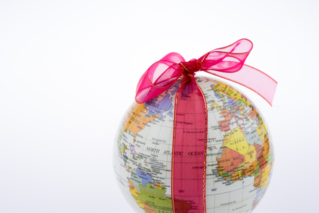 Globe tied with red ribbon on a white backgroundの写真素材