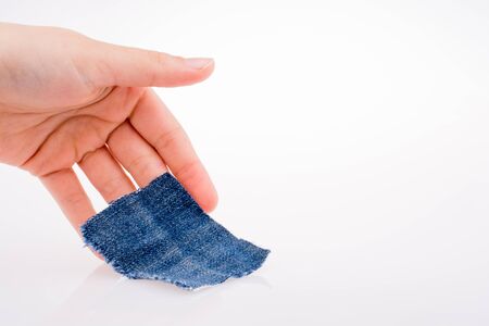 Hand holding a denim fabric piece on white backgroundの写真素材
