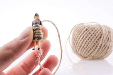 Woman figure in hand beside a linen spool of thread on a white backgroundの写真素材