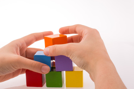 Hand playing with colorful cubes on a white backgroundの写真素材