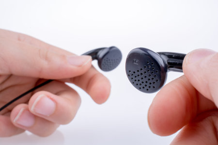 Hand holding a black earphone on a white background