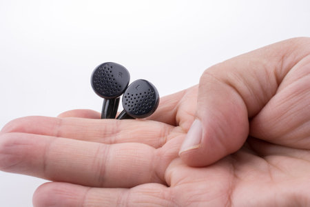 Hand holding a black earphone on a white background
