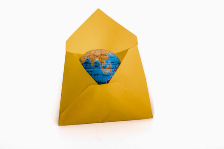 Small earth model in a yellow envelope on a white background