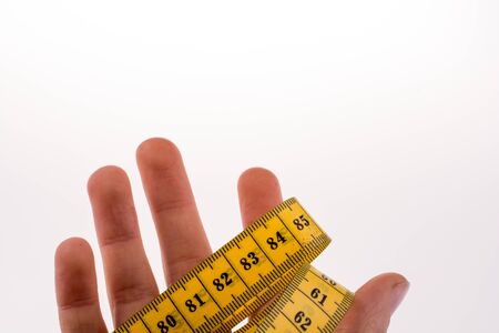 Hand holding a yellow measuring tapeの写真素材
