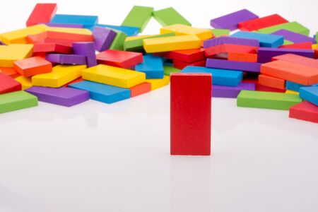 Hand playing with colored domino on white backgroundの写真素材