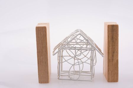 Little metal house  between two domino pieces  on a light  brown color backgroundの写真素材