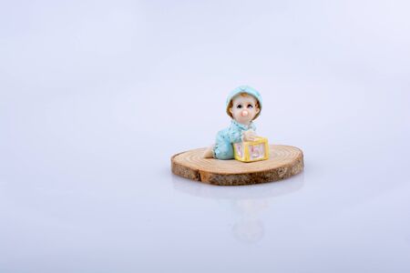 Little baby figure on a piece of wood on a white backgroundの写真素材