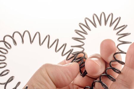 Metal spring form a heart shape in hand on a white backgroundの写真素材