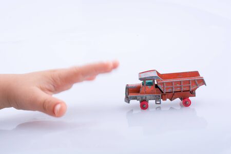 Baby hand is about to grab a red  toy truck on white backgroundの写真素材