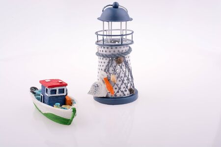 Little colorful model boat and a  lighthouse on white backgroundの写真素材