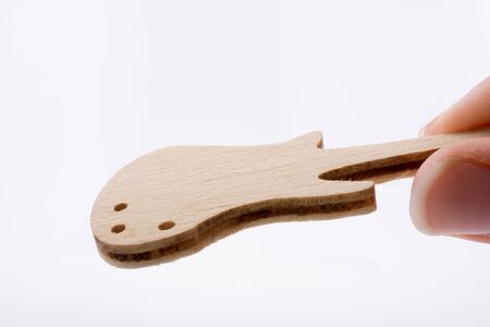 Mini wooden guitar model in hand on a white backgroundの写真素材