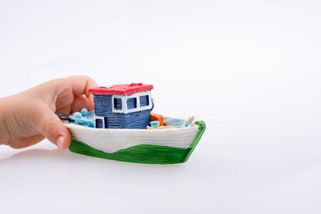 Little colorful model boat in hand on white backgroundの写真素材