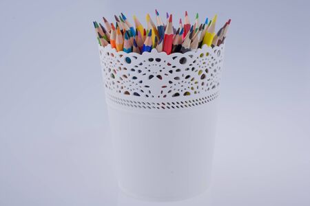 Colorful pencils in a vase on a white backgroundの写真素材