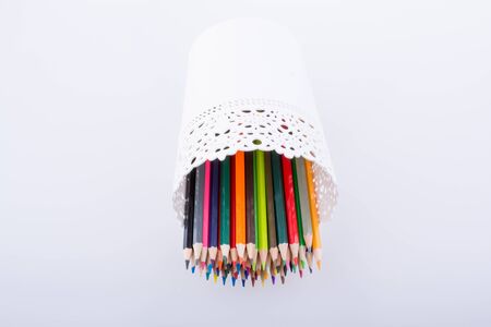 Colorful pencils in a vase on a white backgroundの写真素材