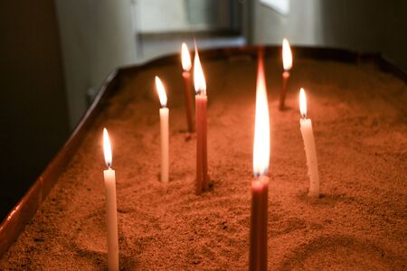 Candles burning over dark background in a churchの写真素材