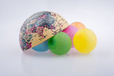 Color balloons are placed around the half a globeの写真素材