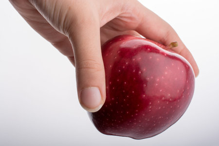 Hand holding a beautiful red apple on a white background