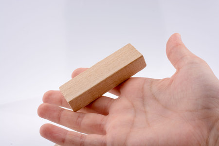 Hand playing with wooden building blocks on white background