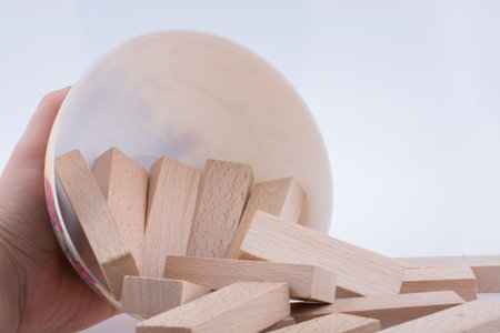 Hand playing with wooden building blocks on white background