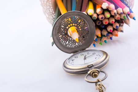 Retro style classic pocket watch and color pencils on white backgroundの写真素材