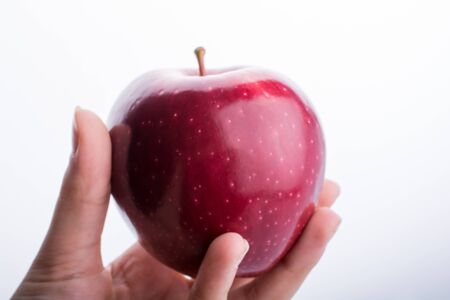Hand holding a beautiful red apple on a white backgroundの写真素材
