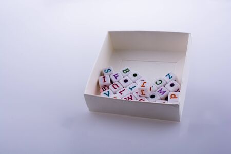 Colorful alphabet letter cubes in a box on a white backgroundの写真素材