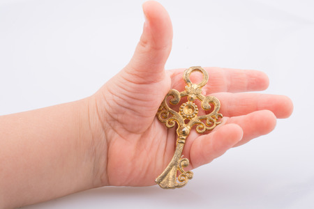 Child hand holding a retro styled decorative keyの写真素材
