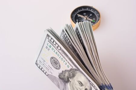 American dollar banknotes by the side of a compass on white backgroundの写真素材