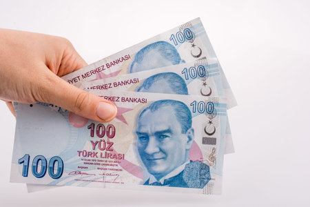 Hand holding 100 Turksh Lira banknotes  on white background