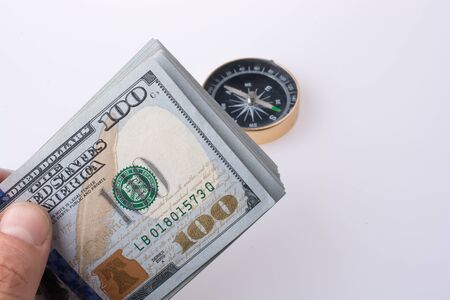 American dollar banknotes by the side of a compass on white backgroundの写真素材