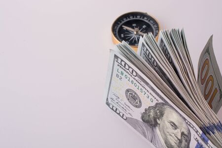 American dollar banknotes by the side of a compass on white backgroundの写真素材