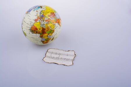 Musical notes on a burnt paper and a little model globeの写真素材