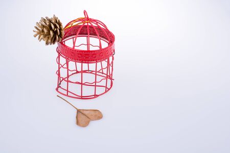 Pine cone tied to a bird cage and a hear shape cut leafの写真素材