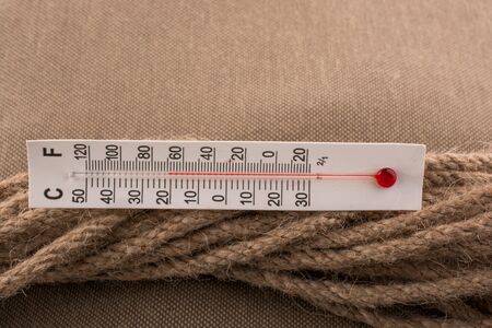 Thermometer placed on a brown rope on a fabric backgroundの写真素材
