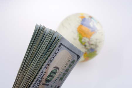 American dollar banknotes by the side of a model globe on white backgroundの写真素材