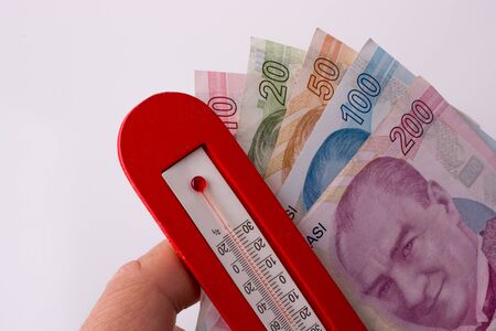 Turkish Lira banknotes by the side of a red color temperature on white backgroundの写真素材