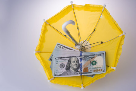 American dollar banknotes placed on an umbrella on white backgroundの写真素材