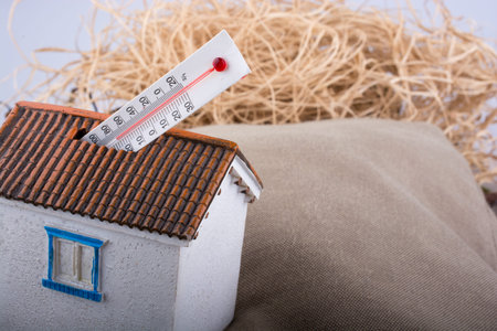 Thermometer measuring high temperature  placed on a little model house