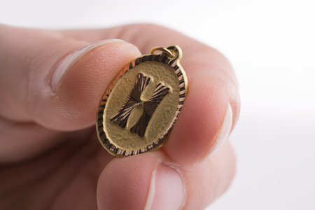 Hand holding a golden Letter H on a white background