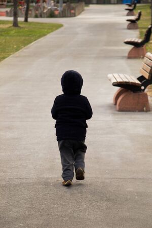 Child walking wooden park bench at a parkの写真素材