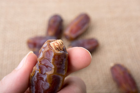 hand holding a date on a linen canvas background