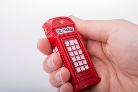 Hand holding a red color phone booth on a white backgroundの写真素材